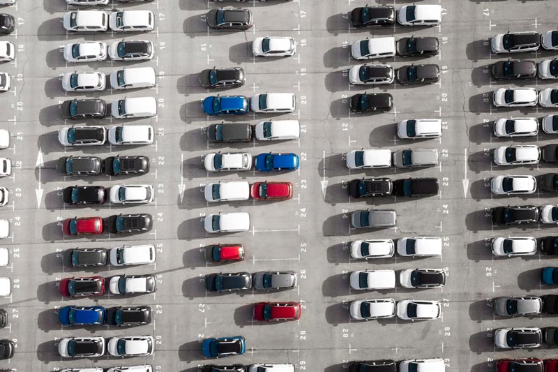 Vogelperspektive auf einen großen Parkplatz bei Gebrauchtwagen Ankauf Lübeck, der mit Reihen weißer Autos gefüllt ist.